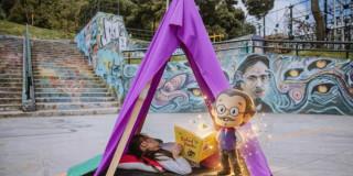 Imagen de niña leyendo Rafael pombo en kiosko en espacio público