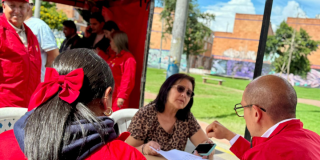 Imagen de funcionarios atendiendo a una señora en una mesa