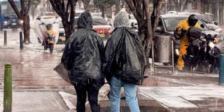 Foto que muestra personas caminando bajo la lluvia 