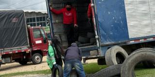 Foto que muestra personas subiendo llantas en desuso en un camion 