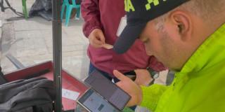 Uniformado de la Policía haciendo verificación e inspección a carreta de compra y venta de celulares robados