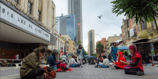 Imagen panorámica de la carrera séptima donde varias personas leen sentados en la vía.