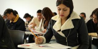 Foto que muestra personas escribiendo en un papel 