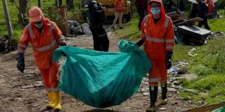 Foto que muestra personas levantando una bolsa con residuos