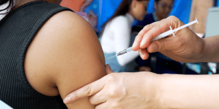 Foto de una enfermera colocando una vacuna en el hombro de una persona