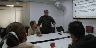 Imagen de una señora junto con un militar durante una reunión