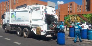 Foto de un camión recolector de basuras y operarios de aseo de LIME en Bogotá.