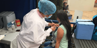 Foto de una enfermera colocando una vacuna en el hombro de una persona