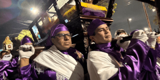 Imagen de dos hombres cargando un imagen de jesucristo