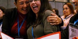 Foto de mujeres abrazandose y sonriendo.