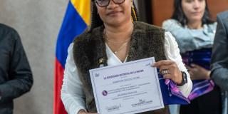 Mujer posando con un certificado de un programa de la Secretaría de la Mujer