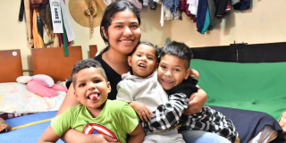 Imagen de una madre sonriendo junto a sus hijos