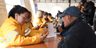 Imagen de una funcionaria mirando el celular con un señor