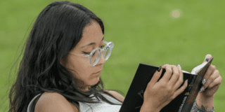 Imagen de una mujer leyendo un libro, sentada comodamente en un parque.
