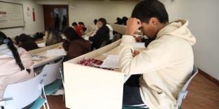 Foto que muestra estudiantes escribiendo en un papel