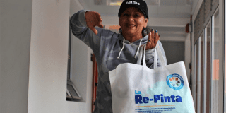 Imagen de una mujer sonriendo y sosteniendo un talego con ropa