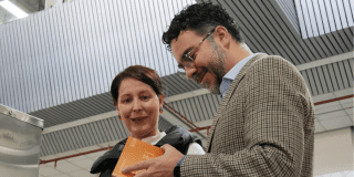 Secretario general lee libro junto a usuaria de la red cade