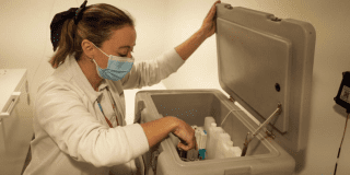 Imagen de un enfermera abriendo una nevera portátil donde se encuentran varias vacunas.