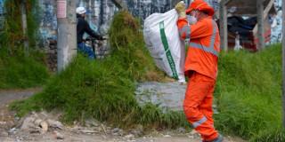 Foto que muestra una persona cargando una bolsa con residuos