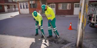 Foto que muestra dos personas barriendo la calle 