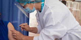 Foto que muestra una enfermera colocando una vacuna