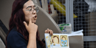 Imagen de una profesora con un libro en el que se ve una ilustración
