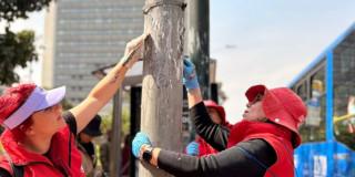 Funcionarios del DADEP limpiando un poste de luz de publicidad no permitida.