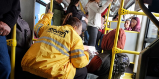 Imagen de una funcionaria atendiendo a un habitante de calle en un bus de TransMilenio