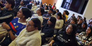 Imagen de jóvenes sentados escuchando a una persona