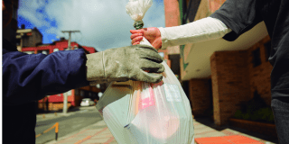 Imagen de una persona entregando una bolsa de basura a un recolector.