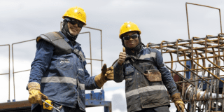 Imagean de dos trabajadores de la obra del Metro de Bogotá vestidos con su uniforme.