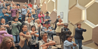 Foto de un grupo de adultos mayores en un auditorio 