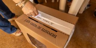 Persona depositando su voto en una urna.
