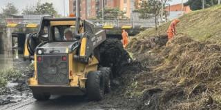 Foto que muestra un carro recolector y personas levantando residuos en un canal
