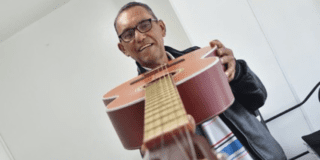 Imagen de Héctor mostrando su guitarra