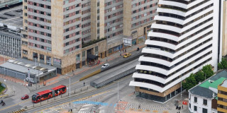 Avenida bogotana con buses TransMilenio, edificios altos y cruces peatonales desde arriba