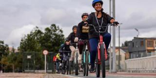 Grupo de mujeres ciclistas pedaleando en ciclovía de Bogotá con cascos alineados