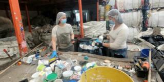 Foto que muestra dos personas con gorros y tapabocas reciclando 