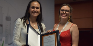 Foto de dos mujeres con un reconocimiento 