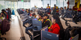 Funcionarios del Centro de Control de TransMilenio monitoreando desde computadores.