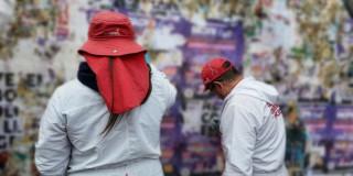 Dos defensores del espacio público retirando publicidad política ilegal del espacio público.