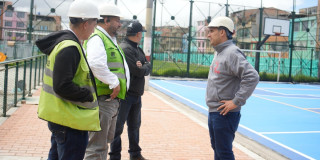 Foto que muestra cuatro personas con casco blanco hablando en un parque