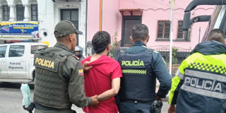 Hombre capturado durante el operativo, rodeado de tres policías.
