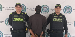 Hombre capturado, de espaldas, en medio de dos policías.