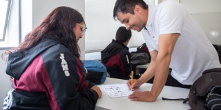 Foto que muestra dos personas hablando y escribiendo en un papel 