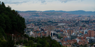 Panorámica de Bogotá con edificios, cerros orientales y cielo parcialmente nublado