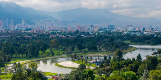 Vista panorámica de Bogotá, lago, senderos y arbolados de la ciudad con vista a montañas y cielo nublado
