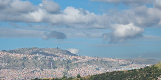 Panorámica de Bogotá con cerros poblados y cielo parcialmente nublado al fondo