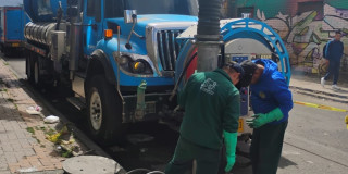 Foto que muestra personas con el uniforme del Acueducto de Bogotá trabajando en una alcantarilla