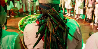 Imagen de señor de espalda con banda de plumas en ritual de fuego 